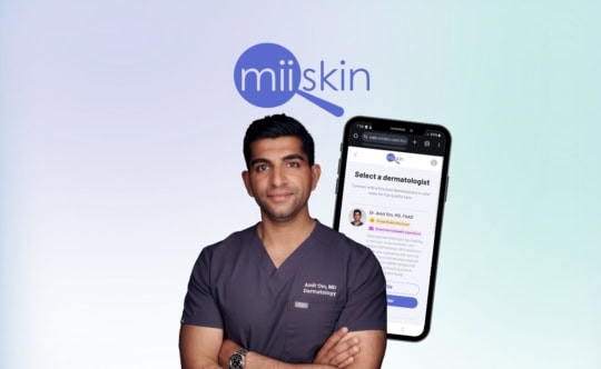 when can online dermatology replace in-person visits dr amit om md faad stands in the foreground with a smartphone behind him displaying the miiskin app on the choose your dermatologist screen highlighting virtual dermatology care