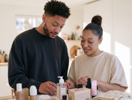 A young man and woman discussing skincare products for acne treatment in a bright, modern room.