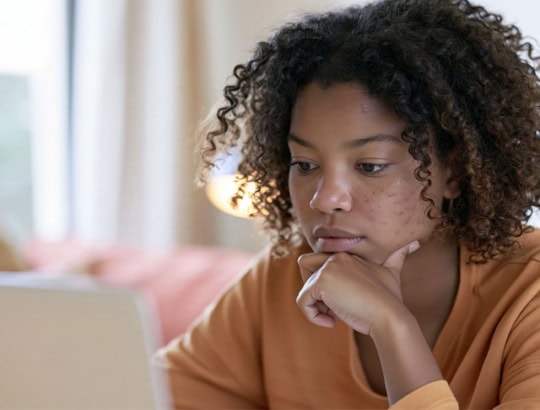 woman with acne in front of the computer comparing online acne services
