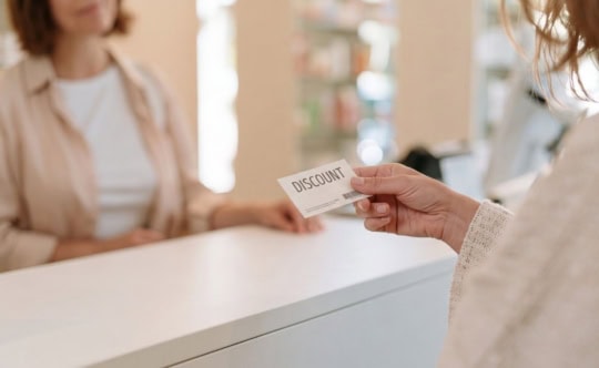 person holding a small pharmacy discount coupon card in their hand